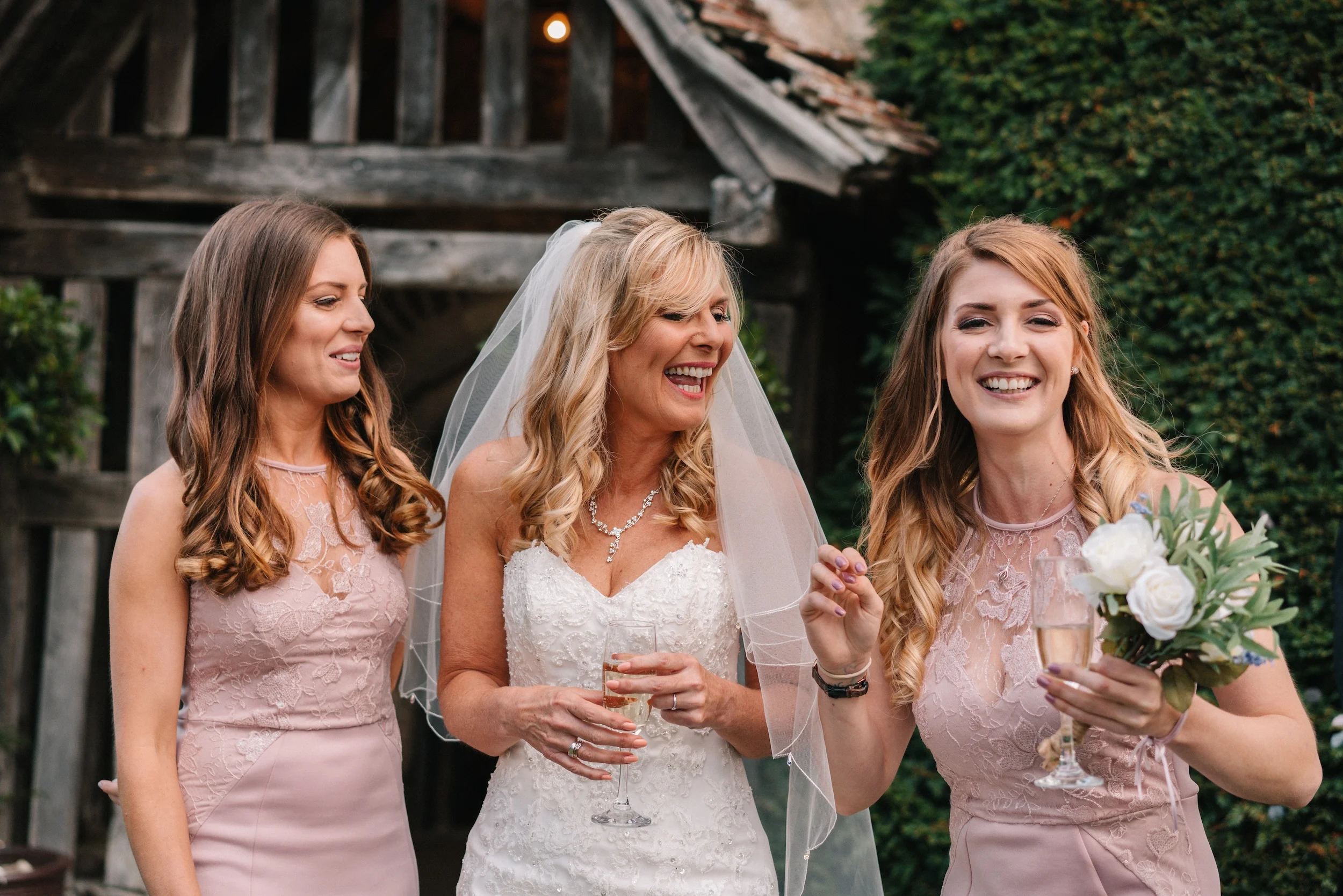 Fiona laughs with her two bridesmaids beside the timber porch