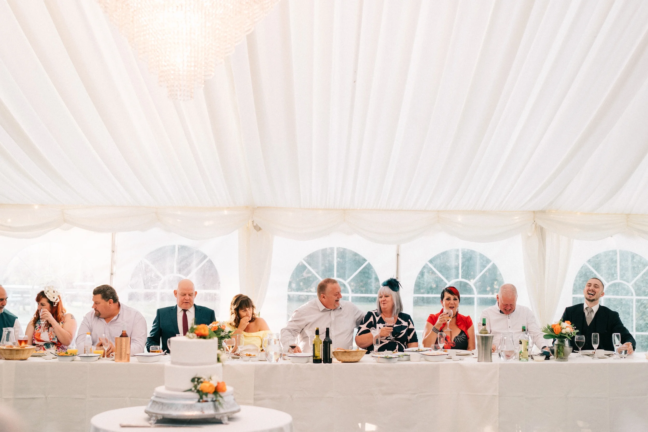 The top table laughs during the speeches in a white marquee