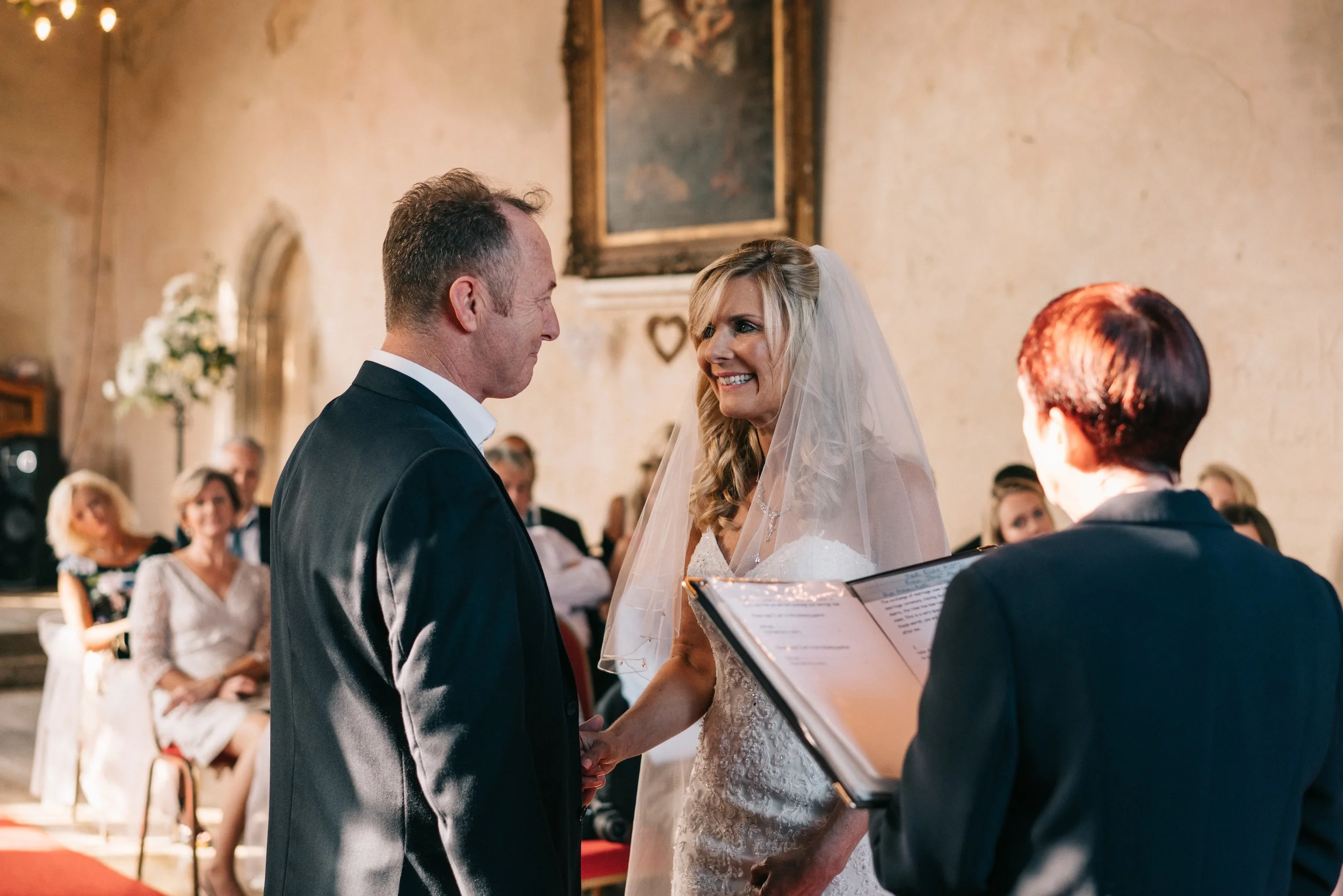 Mark and Fiona face each other during their vows in the Great Hall at Bilsington Priory